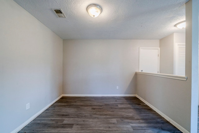 spare room with a textured ceiling and dark hardwood / wood-style floors