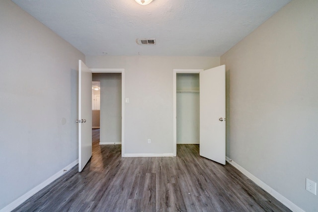 unfurnished bedroom with dark hardwood / wood-style flooring, a textured ceiling, and a closet