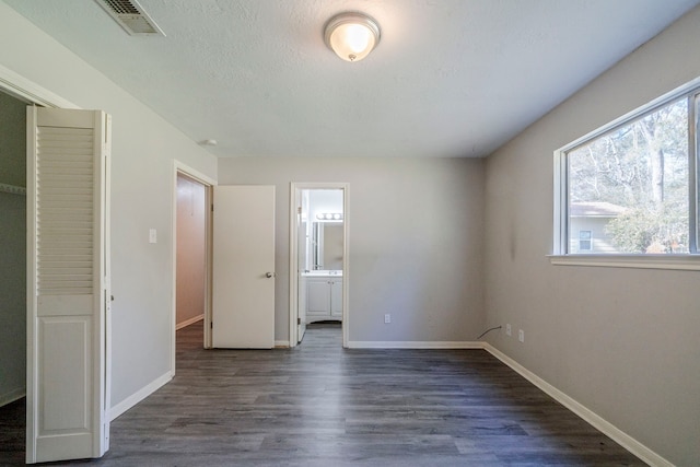 unfurnished bedroom with dark hardwood / wood-style flooring and connected bathroom