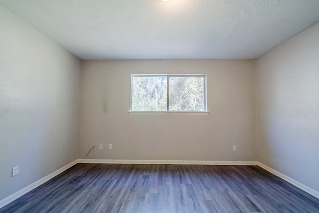 spare room featuring dark hardwood / wood-style flooring and a textured ceiling