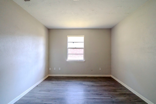 unfurnished room with dark wood-type flooring