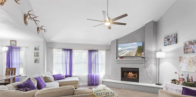 living room featuring ceiling fan, high vaulted ceiling, light hardwood / wood-style floors, and a brick fireplace