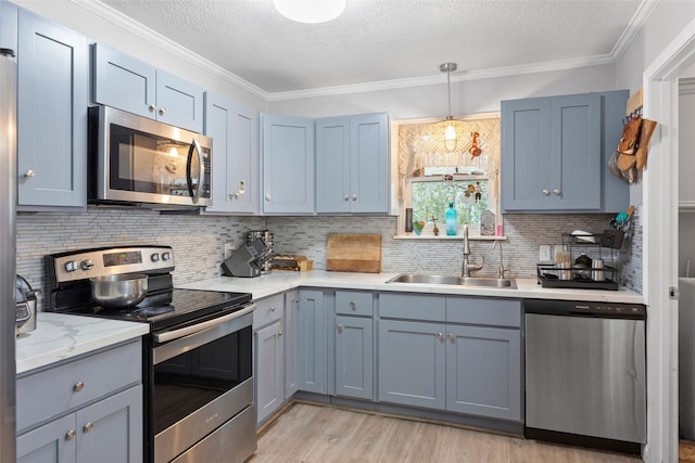 kitchen featuring sink, ornamental molding, a textured ceiling, light hardwood / wood-style floors, and stainless steel appliances