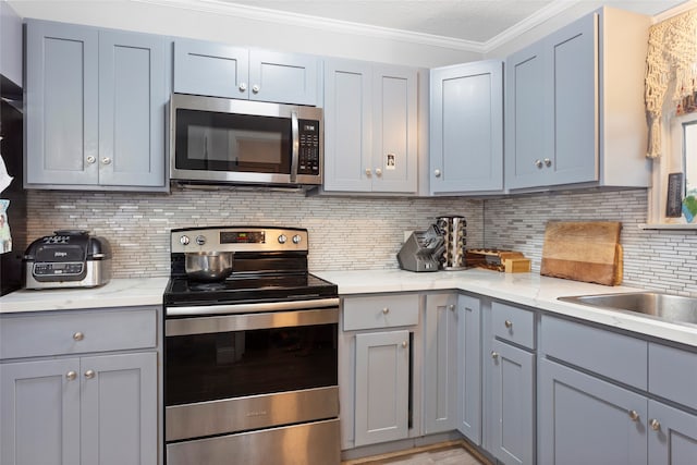 kitchen featuring tasteful backsplash, light stone counters, stainless steel appliances, and ornamental molding