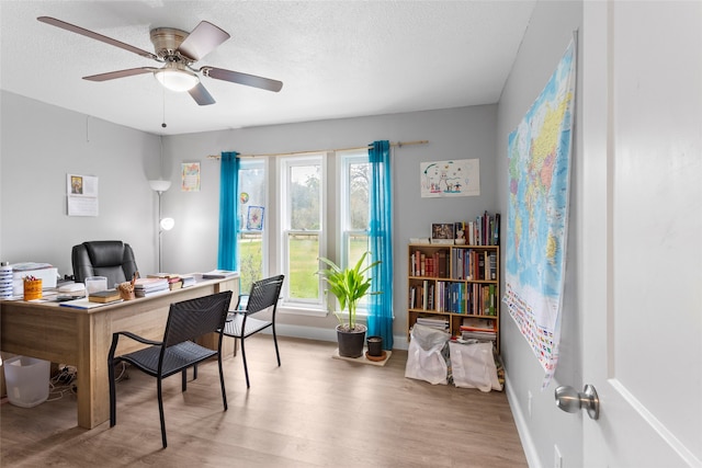 home office with ceiling fan, a textured ceiling, and light hardwood / wood-style flooring