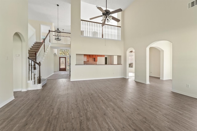 unfurnished living room with ceiling fan, dark hardwood / wood-style floors, and a high ceiling