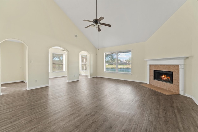 unfurnished living room featuring ceiling fan, dark wood-type flooring, high vaulted ceiling, and a tiled fireplace