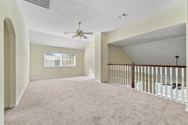 carpeted empty room featuring a textured ceiling, ceiling fan, and lofted ceiling