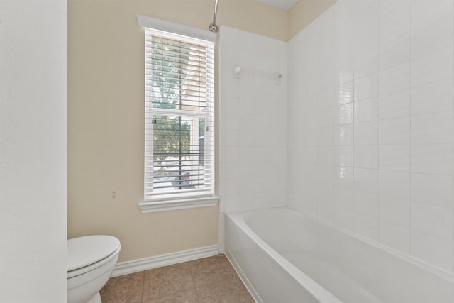 bathroom with tile patterned flooring, toilet, and tiled shower / bath