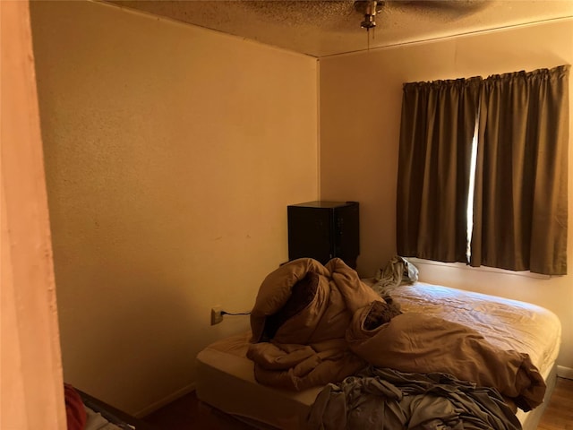 bedroom featuring hardwood / wood-style floors, ceiling fan, and a textured ceiling