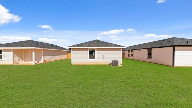 back of house with central air condition unit and a lawn