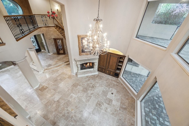 entryway with a high ceiling, ornate columns, a notable chandelier, and a premium fireplace