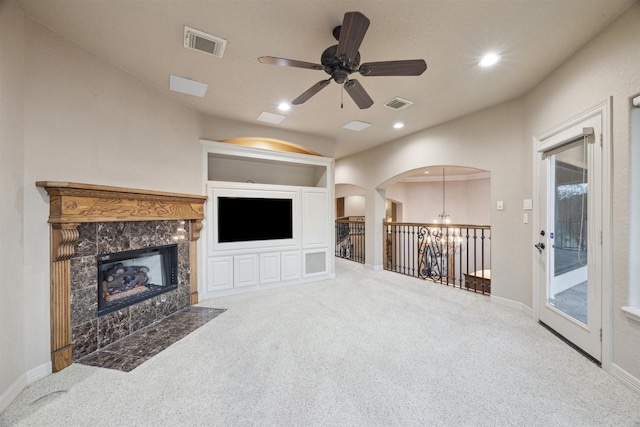 living room with carpet flooring, a fireplace, and ceiling fan with notable chandelier