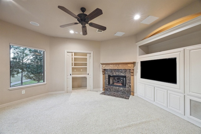 unfurnished living room with ceiling fan, a fireplace, and carpet