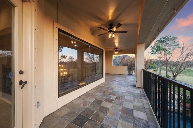 balcony at dusk featuring ceiling fan