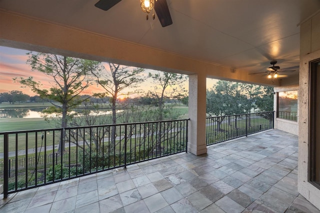 patio terrace at dusk featuring a water view and a balcony