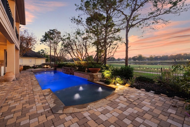 pool at dusk featuring a patio