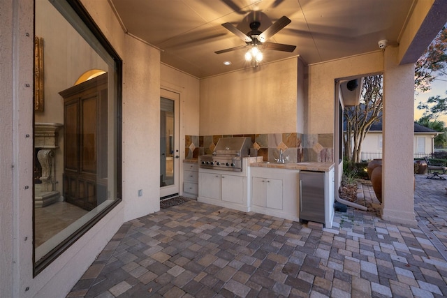 patio terrace at dusk with area for grilling, ceiling fan, and sink