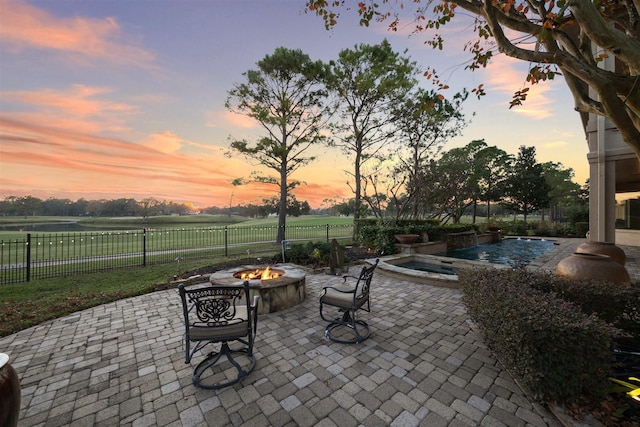 patio terrace at dusk featuring an in ground hot tub and an outdoor fire pit