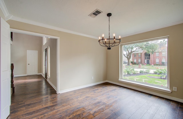 spare room featuring dark hardwood / wood-style floors, a healthy amount of sunlight, crown molding, and an inviting chandelier