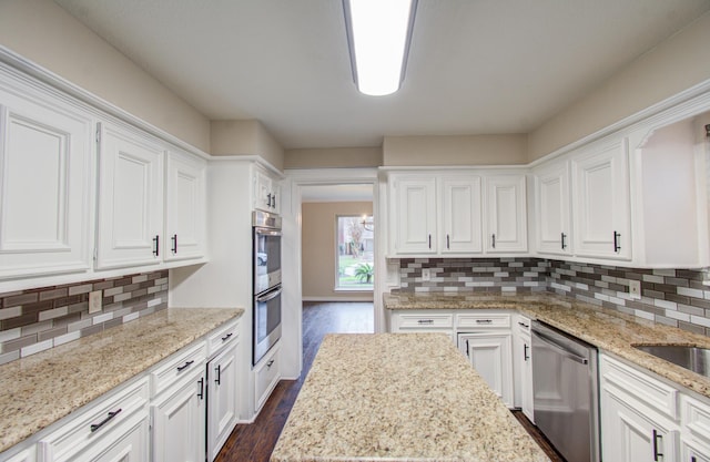 kitchen with dark hardwood / wood-style flooring, white cabinetry, appliances with stainless steel finishes, and tasteful backsplash