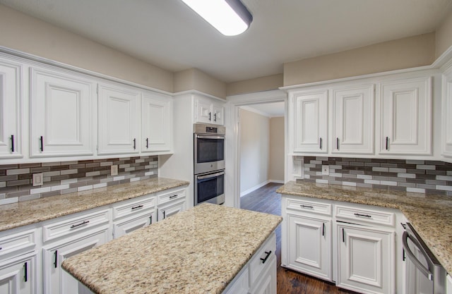 kitchen featuring white cabinetry, light stone counters, dark hardwood / wood-style floors, decorative backsplash, and appliances with stainless steel finishes