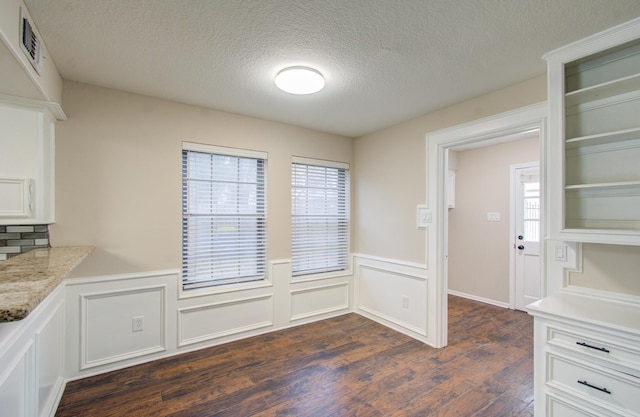 unfurnished dining area with a textured ceiling, dark hardwood / wood-style flooring, and a healthy amount of sunlight