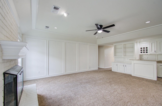 unfurnished living room featuring light carpet, a brick fireplace, and ceiling fan