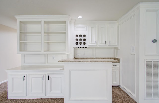 bar featuring white cabinets, dark carpet, and light stone counters