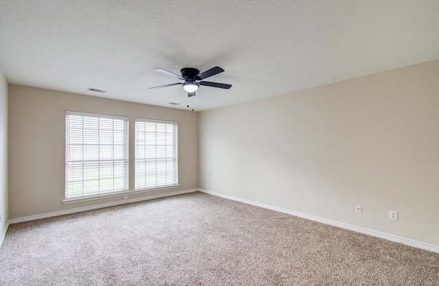 empty room with carpet flooring, ceiling fan, and a textured ceiling