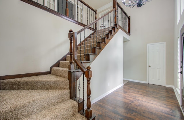 staircase featuring a high ceiling, hardwood / wood-style flooring, and a notable chandelier