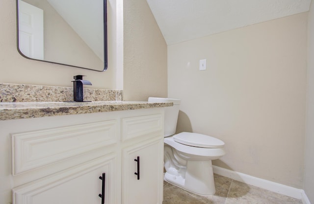 bathroom with tile patterned flooring, vanity, vaulted ceiling, and toilet