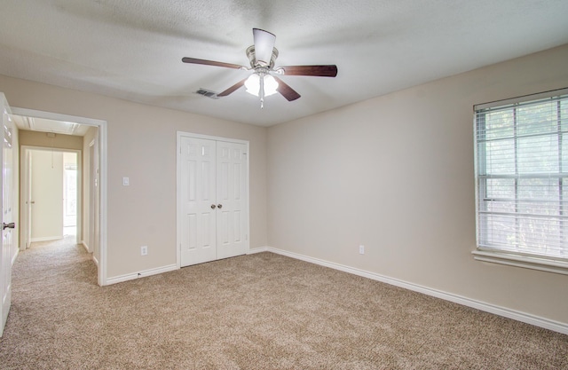 unfurnished bedroom with multiple windows, light carpet, a closet, and ceiling fan