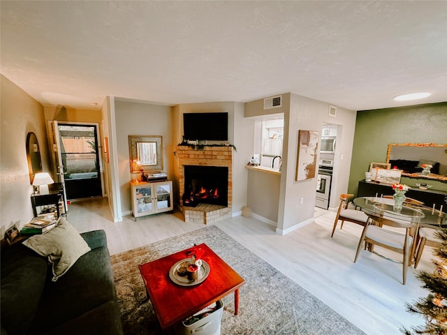 living room with light wood-type flooring and a brick fireplace