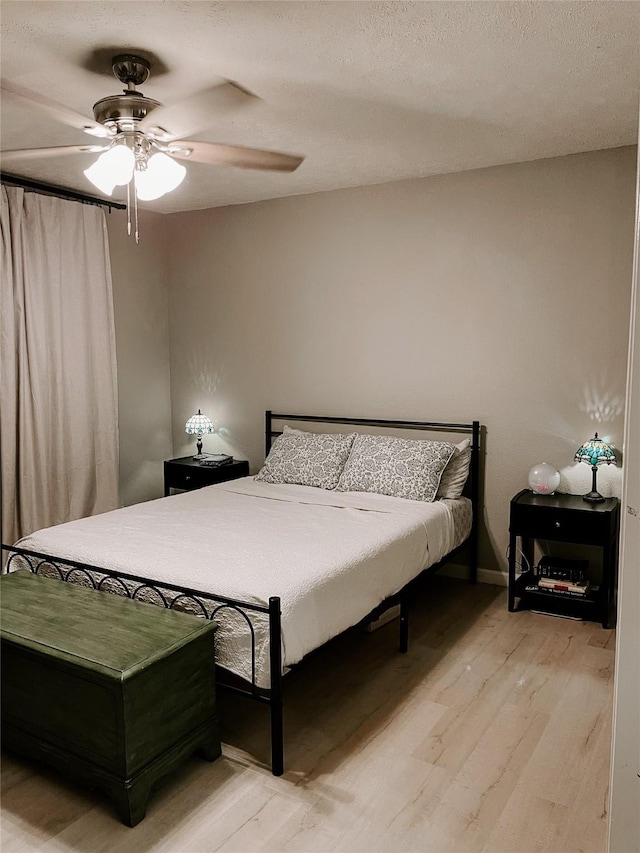 bedroom with ceiling fan, light hardwood / wood-style flooring, and a textured ceiling