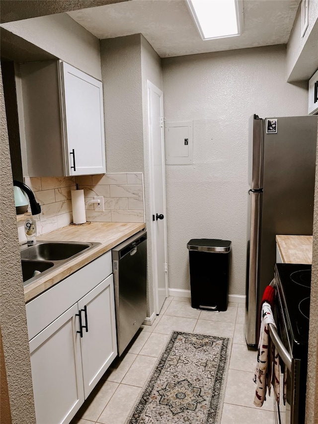 kitchen featuring dishwasher, sink, light tile patterned floors, tasteful backsplash, and white cabinets