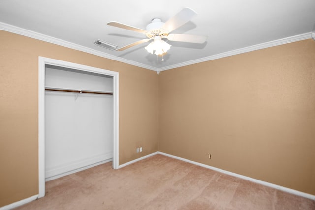 unfurnished bedroom featuring ceiling fan, light colored carpet, a closet, and crown molding