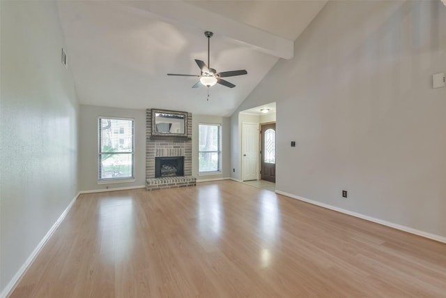 unfurnished living room with ceiling fan, a brick fireplace, beamed ceiling, high vaulted ceiling, and light wood-type flooring