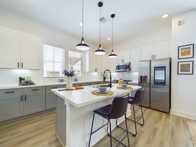 8321 Springwood Creek Ln, Houston, TX 77055 - kitchen with stainless steel appliances, a sink, gray cabinetry, backsplash, and light wood finished floors