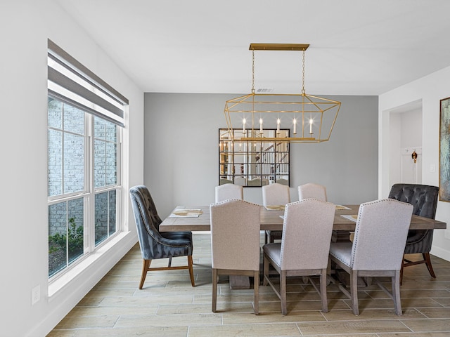 dining area featuring a healthy amount of sunlight, light wood-type flooring, and a notable chandelier