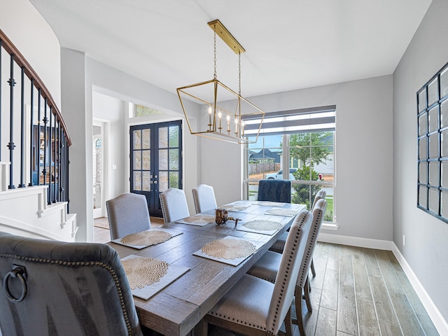 dining room with a chandelier, light wood-type flooring, and french doors