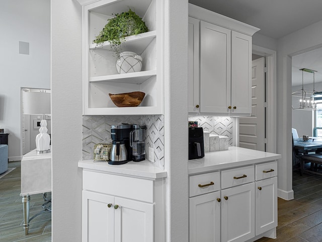 bar featuring an inviting chandelier, white cabinets, hanging light fixtures, dark hardwood / wood-style floors, and decorative backsplash