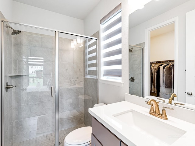 bathroom with an enclosed shower, vanity, and toilet