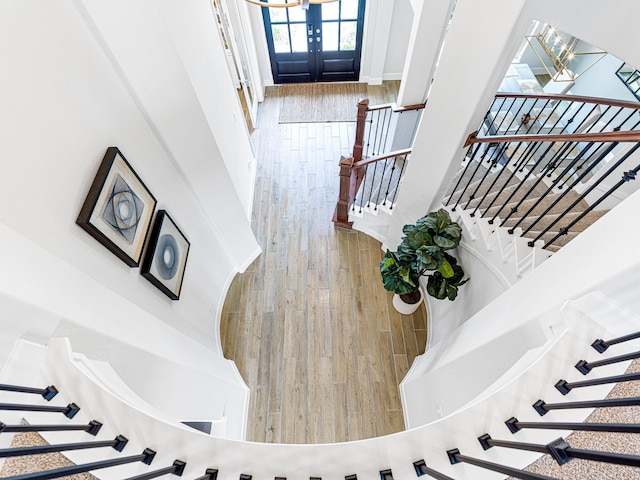 stairs featuring french doors, a towering ceiling, and hardwood / wood-style floors