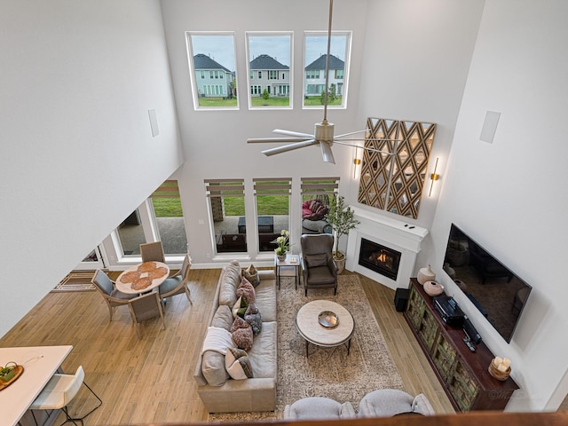 living room with a high ceiling, light hardwood / wood-style flooring, plenty of natural light, and ceiling fan