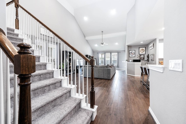 stairway featuring a fireplace, hardwood / wood-style flooring, high vaulted ceiling, and ceiling fan