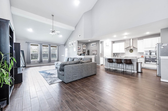 living room featuring beam ceiling, dark hardwood / wood-style flooring, high vaulted ceiling, and ceiling fan