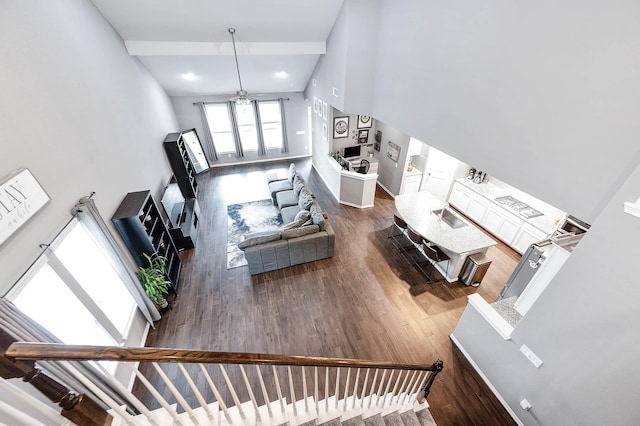 living room with ceiling fan, wood-type flooring, sink, and high vaulted ceiling