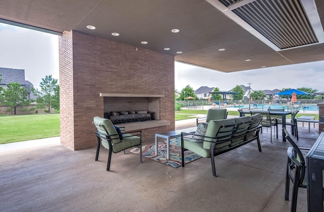 view of patio featuring a swimming pool and an outdoor brick fireplace