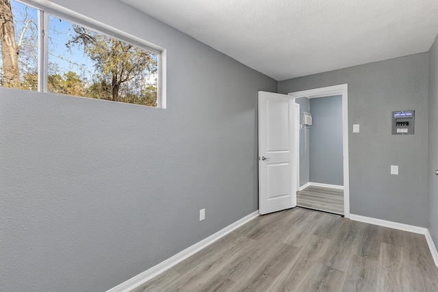 spare room featuring a textured ceiling and light hardwood / wood-style floors